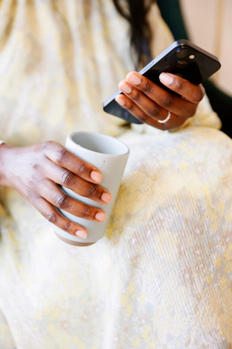 woman holding phone and coffee 865x1298